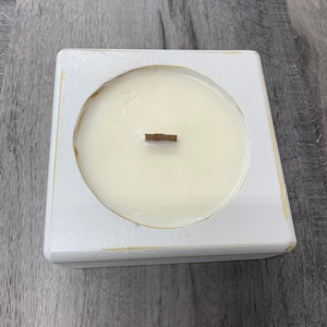 May include: White square wooden candle holder with a white candle and a wooden wick. The candle holder has a distressed white paint finish.
