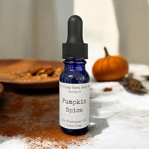May include: A blue glass bottle with a black dropper top. The bottle is labeled "The Tipsy Goat Soap Co. Warsaw, IN" and "Pumpkin Spice Car Freshener Oil 0.5oz (14g)".