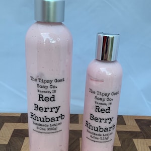 May include: Two pink lotion bottles with silver caps and white labels. The labels read "The Tipsy Goat Soap Co. Red Berry Rhubarb Handmade Lotion." The larger bottle is 8.0oz (230g), and the smaller is 4.0oz (115g).