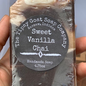 May include: A bar of brown and white soap with a black and white label that reads "The Tipsy Goat Soap Company, Warsaw, Indiana, Sweet Vanilla Chai, Handmade Soap, 4.75oz."