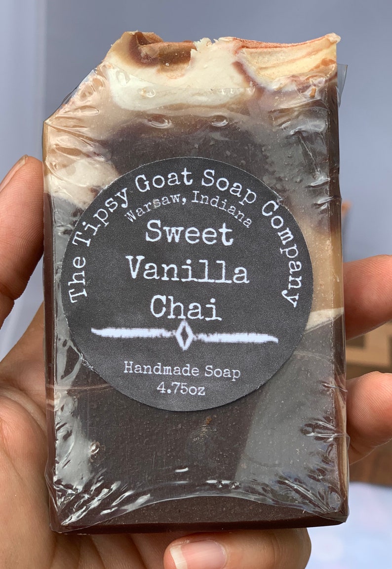 May include: A bar of brown and white soap with a black and white label that reads "The Tipsy Goat Soap Company, Warsaw, Indiana, Sweet Vanilla Chai, Handmade Soap, 4.75oz."
