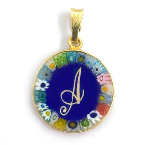 May include: A gold pendant with a blue glass circle featuring the letter 'A' in gold script. The circle is surrounded by a border of colourful millefiori glass.