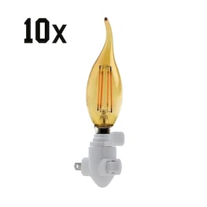 May include: A flame-shaped LED light bulb with a warm amber glow, mounted on a white night light base. The text "10x" is in the upper left corner. The bulb has vertical filaments and a curved tip, designed to mimic a flickering flame.