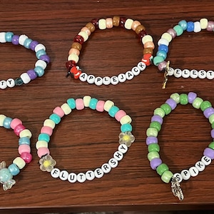 May include: Ten colorful beaded bracelets with different names on them, including "Dash", "Pinkie", "Fluttershy", "Spike", and "Cadence".