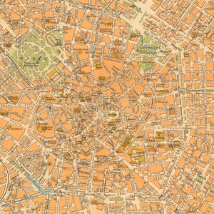 May include: A vintage map of Milan, Italy, with detailed street names and landmarks. The map is printed in shades of orange and brown on a cream-colored background.