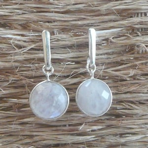 Peut inclure: Une paire de boucles d'oreilles pendantes en argent avec des pierres de lune rondes et irisées.