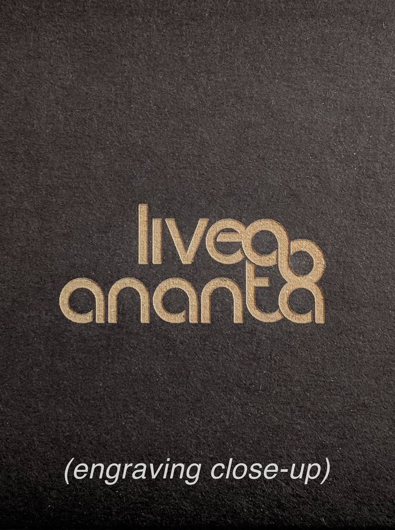 May include: Close-up of an engraved logo on a black surface. The logo reads "liveda ananta" in a gold font.