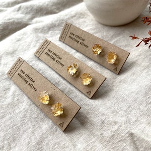 May include: Three pairs of raw citrine earrings on brown cards with the text "raw citrine sterling silver" and the letter "A" printed on each card.