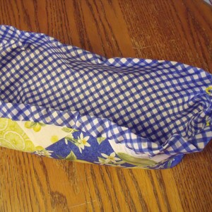 Puede incluir: Una cesta forrada con tela vichy azul y blanca con un estampado de lim&oacute;n y flores en el exterior. La cesta est&aacute; vac&iacute;a y lista para ser llenada.