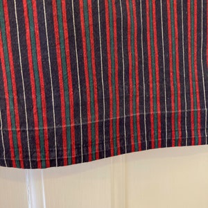 May include: Close-up of a striped fabric with red, green, and white stripes on a dark blue background.