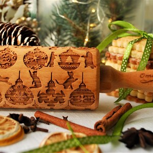 May include: A wooden rolling pin with a Christmas-themed design featuring ornaments, cats, and stars. The rolling pin is engraved with the words "Oma Marta".