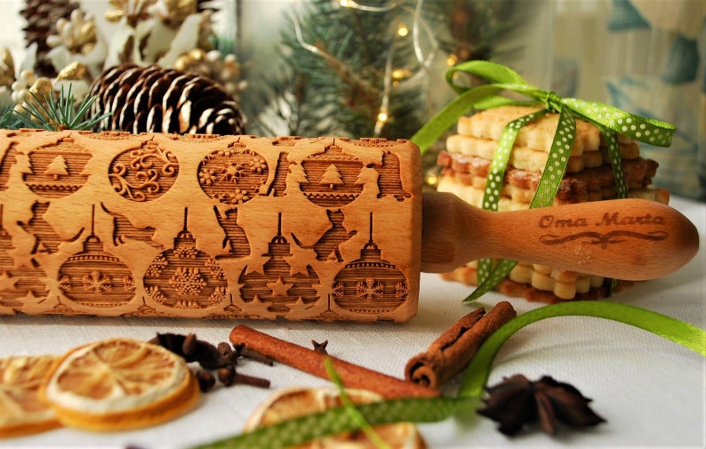 May include: A wooden rolling pin with a Christmas-themed design featuring ornaments, cats, and stars. The rolling pin is engraved with the words "Oma Marta".