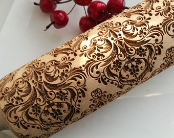 May include: A wooden rolling pin with a detailed, intricate, carved design of a floral pattern. The design is in shades of brown and black.