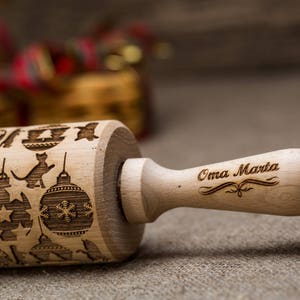 May include: A wooden rolling pin with a Christmas-themed design, including ornaments and cats. The handle is engraved with the text "Oma Marta".