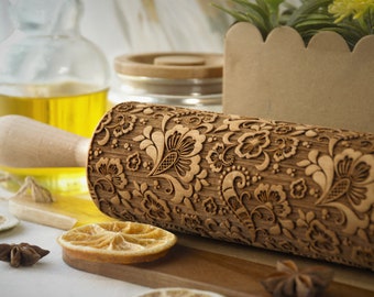 May include: A wooden rolling pin with a carved floral design. The rolling pin is made of natural wood and has a handle on one end.