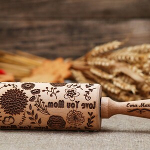May include: A wooden rolling pin with a floral design and the text "Love you Mom" engraved on it. The handle is engraved with the name "Oma Marta".