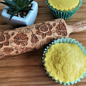 May include: A wooden rolling pin with a floral design engraved into the surface. The rolling pin is personalized with the text "Oma Marta".