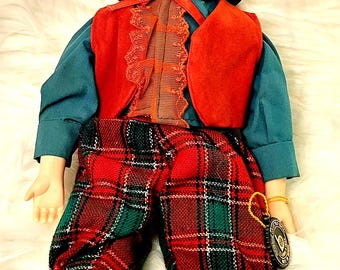 Vintage porcelain boy doll, dressed in christmas plaid outfit and hat, with stand