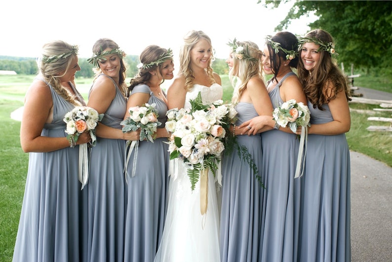 May include: A group of bridesmaids in light blue dresses with floral headbands and bouquets. The bride is in a white dress and holding a large bouquet of white and peach flowers.