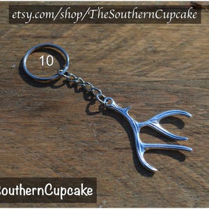 May include: Silver key chain with a deer antler design. The keychain has a silver ring with the number 10 on it.