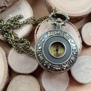 Montre vintage, à gousset env 4,5cm de diamètre,signes astrologiques,Australie, métal façon bronze,chaîne 70 cm, french touch,pile,mixte