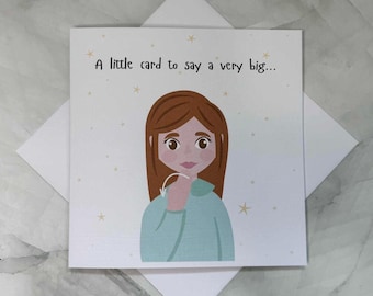 Può includere: Biglietto di auguri con un'illustrazione a cartoni animati di una persona con i capelli castani e un top blu. La carta ha il testo "A little card to say a very big..." ed è decorata con piccole stelle gialle. La carta è su una busta bianca.