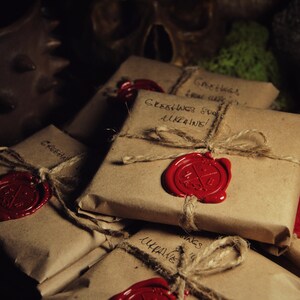 May include: A stack of brown paper packages tied with twine and sealed with red wax. Each package has handwritten text that says "Greetings from Ukraine!"