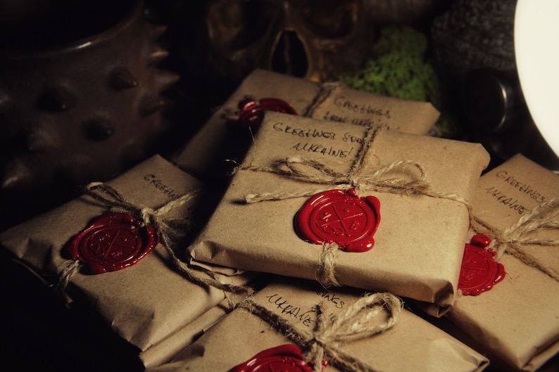 May include: A stack of brown paper packages tied with twine and sealed with red wax. Each package has handwritten text that says "Greetings from Ukraine!"