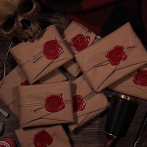 May include: A collection of brown paper packages sealed with red wax stamps and tied with twine. The packages are arranged on a wooden surface with a skull, tools, and other items in the background. The overall theme is vintage or antique.