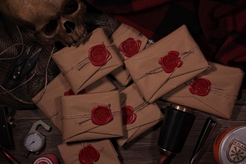 May include: A collection of brown paper packages sealed with red wax stamps and tied with twine. The packages are arranged on a wooden surface with a skull, tools, and other items in the background. The overall theme is vintage or antique.