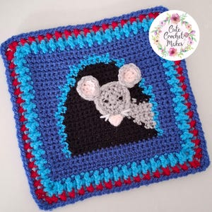 May include: A square crochet patch featuring a gray mouse peeking out from a black hole. The border consists of alternating rows of blue and red yarn. A circular logo in the corner displays the text Cute Crochet Makes surrounded by floral art.