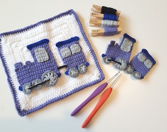 May include: A purple and gray crocheted train with two cars and wheels. The train is on a white and purple crocheted square. There are two crochet hooks and yarn in different colors on a white surface.