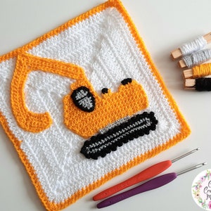 Peut inclure: Un carré crocheté représentant un excavateur jaune et noir. Le carré est bordé d'orange et a un fond blanc. L'image montre également des fils de différentes couleurs et des crochets à crochet.