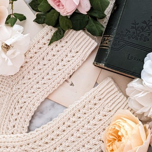 Peut inclure: Chaussettes en tricot cr&egrave;me avec un motif ajour&eacute; d&eacute;coratif. Les chaussettes sont pr&eacute;sent&eacute;es avec des roses roses et blanches, des livres anciens et de la papeterie ancienne, cr&eacute;ant une esth&eacute;tique romantique et vintage.