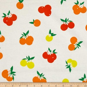May include: A white fabric featuring a repeating pattern of orange, red, and yellow citrus fruits with green leaves and white blossoms. A ruler at the bottom shows a scale of 12 inches, indicating the size of the printed fruit motifs.