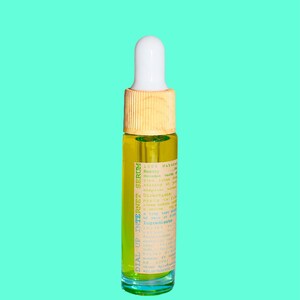 May include: A small glass bottle of serum with a white dropper top and a wooden collar. The bottle contains a yellow liquid and has a label with the text "DIAL UP INTERNET SERUM". The background is a solid teal color.