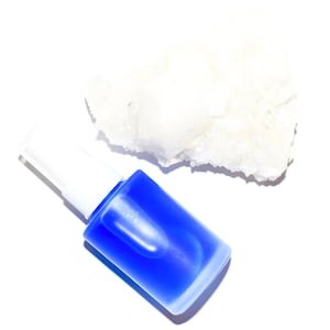 May include: A blue glass bottle with a white pump top and a white, rough-textured rock.