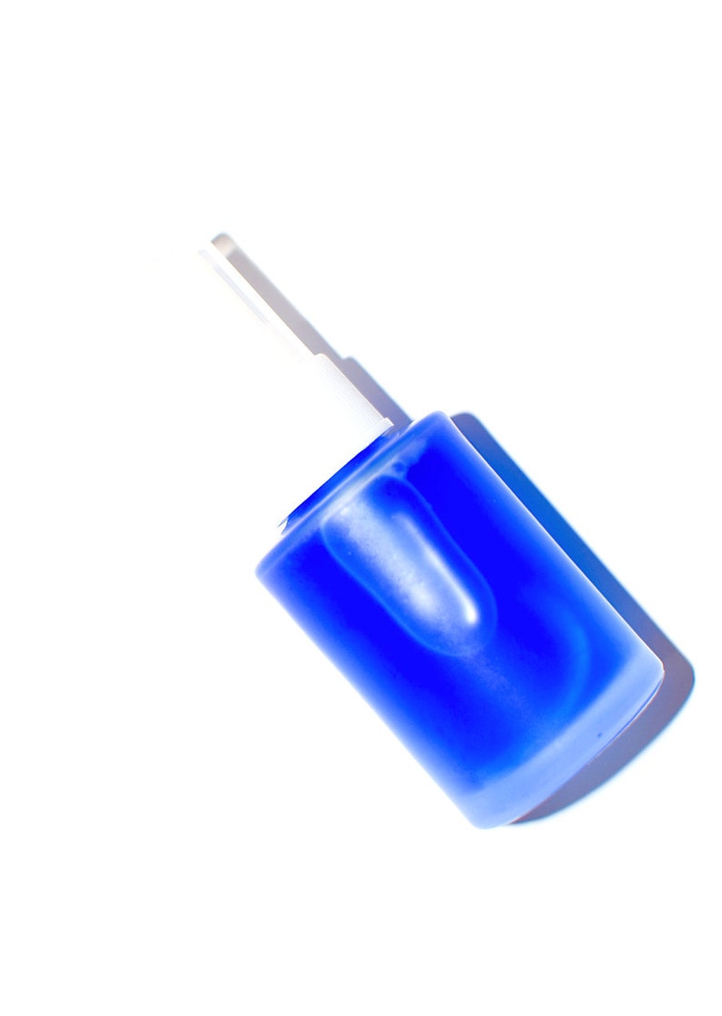 May include: A blue glass bottle with a white dropper top. The bottle is lying on its side.
