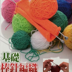 May include: A collection of colorful yarn balls in pink, green, orange, white, blue, and purple, with knitting needles and an orange knitted piece. The image also features a book with Japanese text and a small photo of hands knitting.