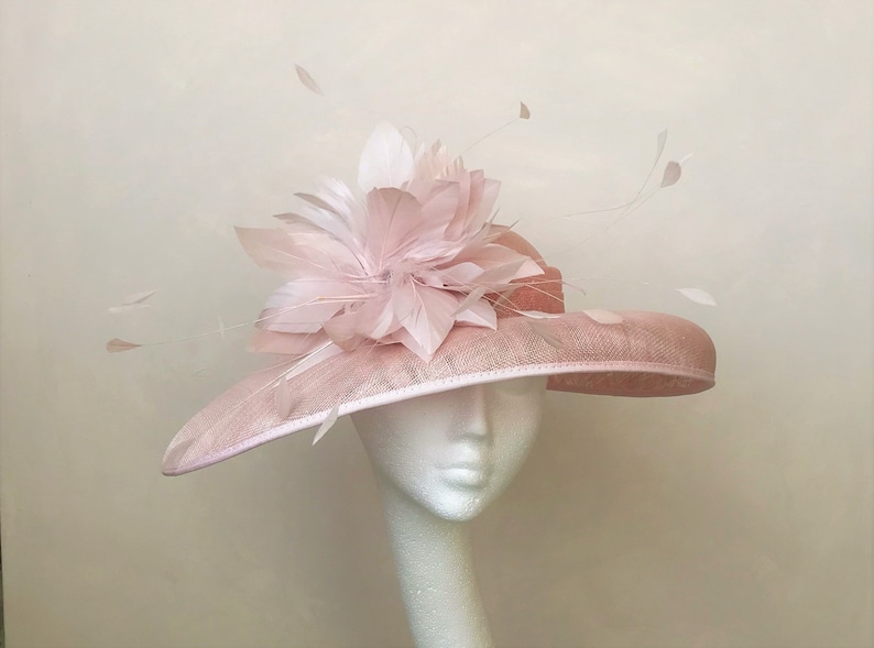 May include: A wide-brimmed hat in pink with a large pink flower made of feathers on top.