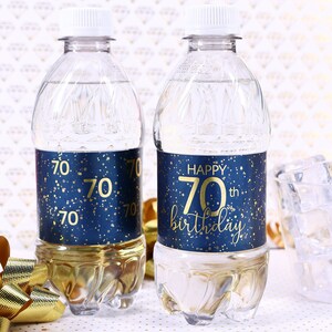 May include: Two clear plastic water bottles with blue and gold labels. The labels have a gold glitter background and say "Happy 70th birthday".