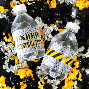 May include: Two clear plastic water bottles with white caps and labels that read "UNDER CONSTRUCTION" in yellow and black. The labels have a diamond plate design. The bottles are surrounded by yellow, black, and silver metallic streamers.