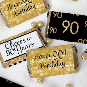 May include: Gold and black chocolate bar wrappers with the text "Happy 90th Birthday", "Cheers to 90 Years", and "90" printed on them.