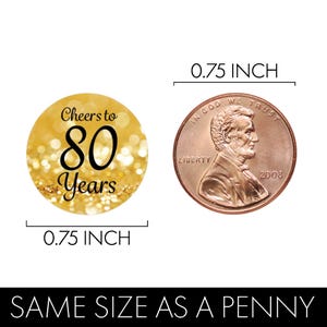 Puede incluir: Pegatina redonda de color dorado y negro con el texto "Cheers to 80 Years" sobre un fondo de purpurina dorada. La pegatina tiene un di&aacute;metro de 0,75 pulgadas, el mismo tama&ntilde;o que una moneda de un centavo.