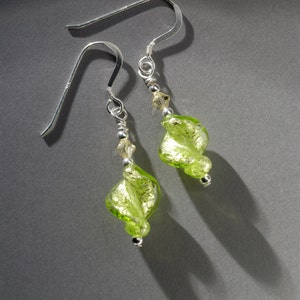 May include: A pair of silver earrings with green glass beads. The beads are swirled and have gold flecks.