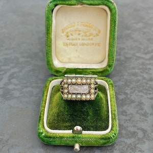 May include: A vintage ring with a rectangular setting filled with small white pearls, set in a green velvet ring box. The box is labeled "Turner & Townsend, Albey House, Ely Place, London, EC."
