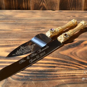 May include: Gold wedding cake knife and server set with jeweled handles. The knife is engraved with "Mr. & Mrs. Remenda June 22, 2018".