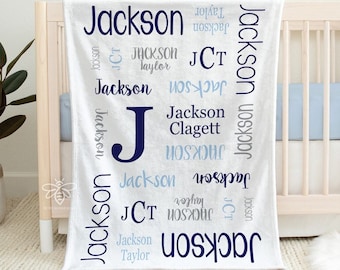 May include: White minky fleece baby blanket with the name "Jackson" repeated in blue and light blue lettering. The blanket is 30 inches by 40 inches.