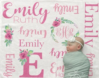 May include: A white minky fleece baby blanket with pink and green floral designs and the name "Emily Ruth" repeated multiple times. The blanket also features a monogrammed "EHR" in a floral wreath. The blanket measures 30x40 inches.