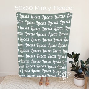 May include: A sage green minky fleece blanket with the name "Lucas" repeated in white text.
